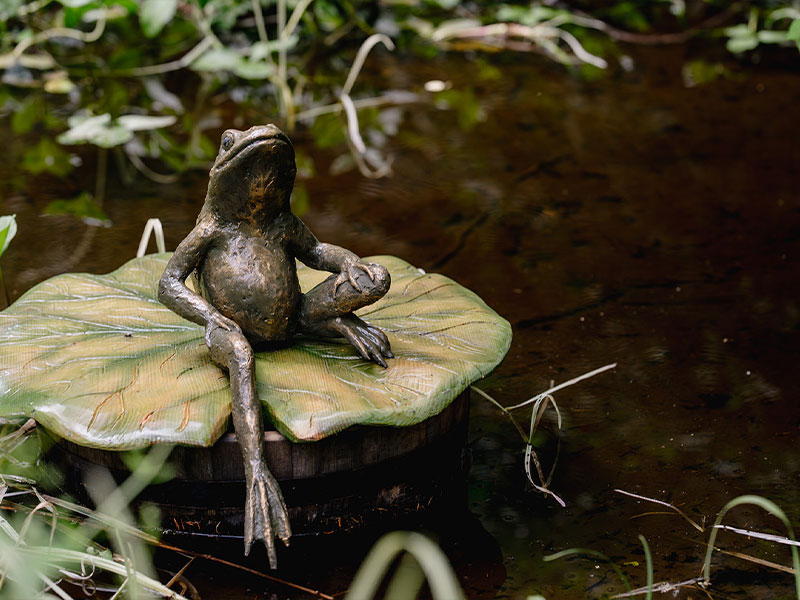Jeremy Fisher sculpture sitting on a lily pad.