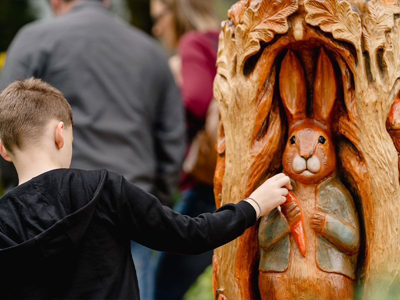 Child interacting with a tactile Beatrix Potter character carving.