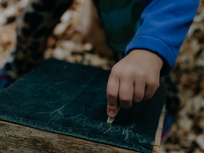 Child using a tactile drawing activity as part of an interactive outdoor trail