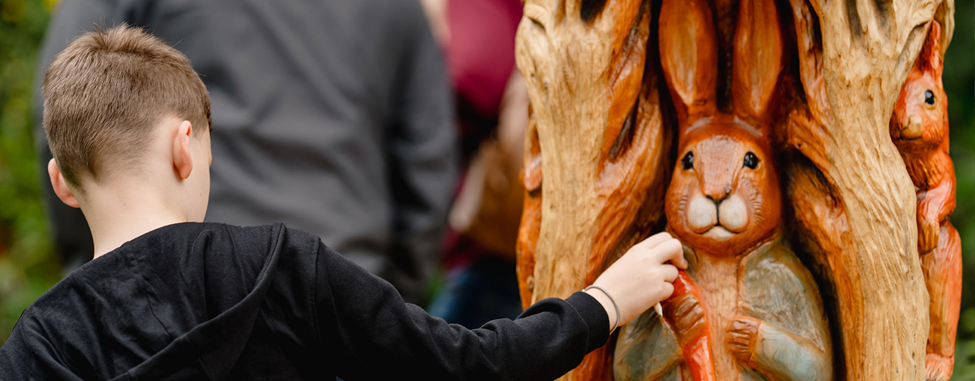 Child touching a tactile rabbit sculpture on the Beatrix Potter Garden Trail